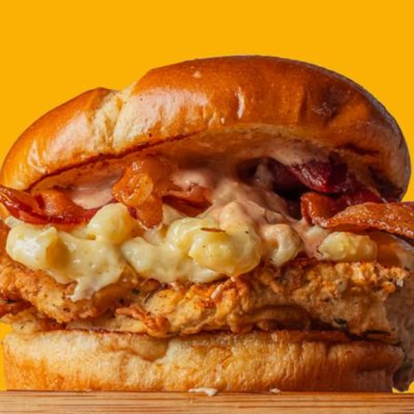 BurgerTen and ChickenToo's chicken sandwich with mac and cheese, bacon, and sauce on a brioche bun.