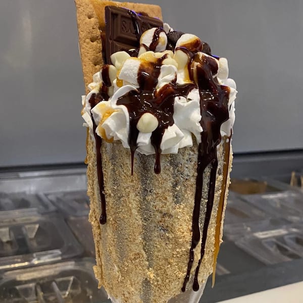 S'mores milkshake with whipped cream, chocolate syrup, caramel, marshmallows, and a graham cracker.